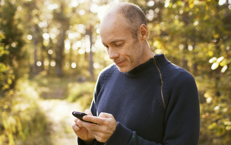 Man med mobiltelefon i skogen. Foto: Susanne Walström