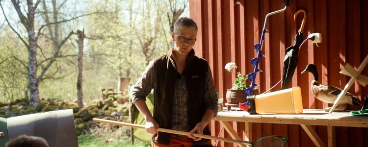 Kvinna med håv berättar något för en liten publik.