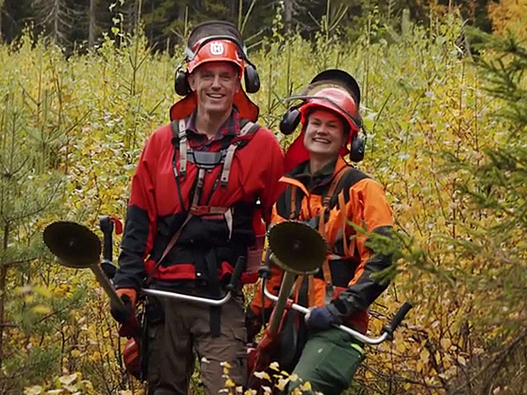 Två glada skogsarbetare med röjsågar