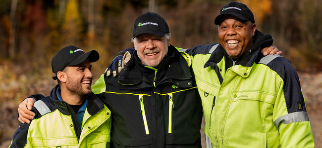 Tre glada män håller varandra om axlarna. Foto: Malin Grönborg