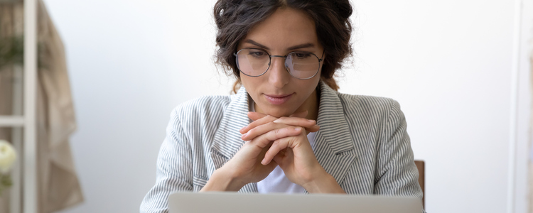 Kvinna med glasögon tittar på webinarium på laptop