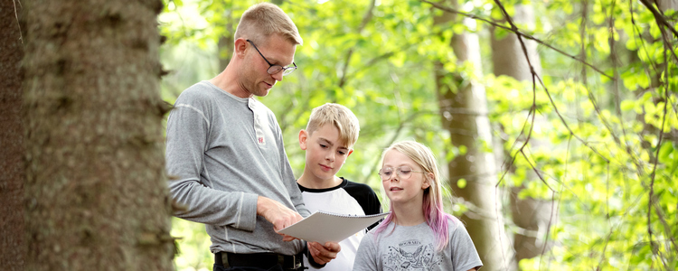 Pappa och två barn tittar i skogsbruksplanen.  Foto: Camilla Zilo